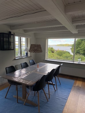 Un coin repas comprenant une table, des chaises, une lampe et donnant sur un lac.