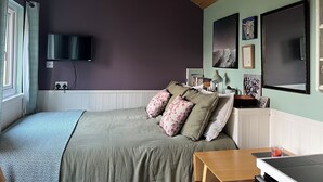 Une chambre à coucher avec un lit, une télévision, un bureau et une fenêtre.