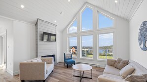 Un vaste salon doté d’un haut plafond, de grandes fenêtres et offrant une vue sur l’extérieur.