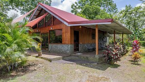 A wooden house with a red roof, surrounded by tropical plants and trees. - Casa Sloth, enchanting private house near La Fortuna. (Provincia de Alajuela)