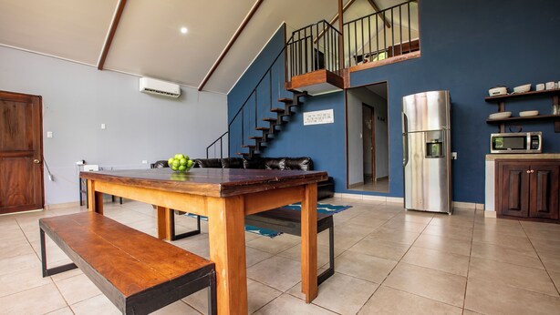 A spacious kitchen with a wooden table, a built-in microwave, and a stainless steel refrigerator. - Casa Sloth, enchanting private house near La Fortuna. (Provincia de Alajuela)