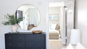 Une chambre moderne avec une commode sombre, un miroir rond et une plante.