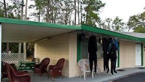 A small building with a green roof, a covered porch with wicker chairs, and a table. - High Springs Country Inn (High Springs)