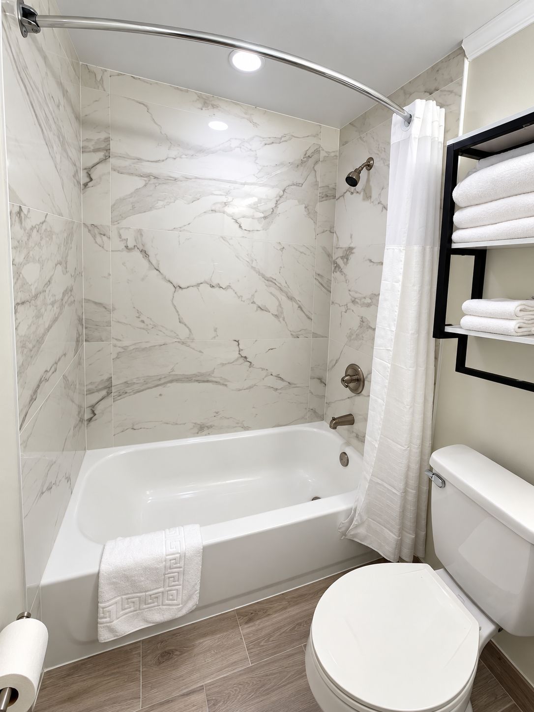 A modern bathroom with a bathtub, toilet, and a shower area.