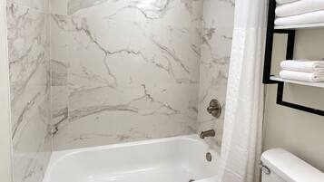 A modern bathroom with a bathtub, toilet, and a shower area.