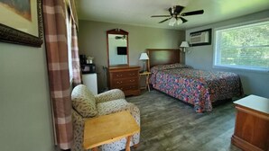 A bedroom with a bed, a chair, a dresser, a ceiling fan, a window with blinds, and a wall-mounted air conditioner. - High Springs Country Inn (High Springs)