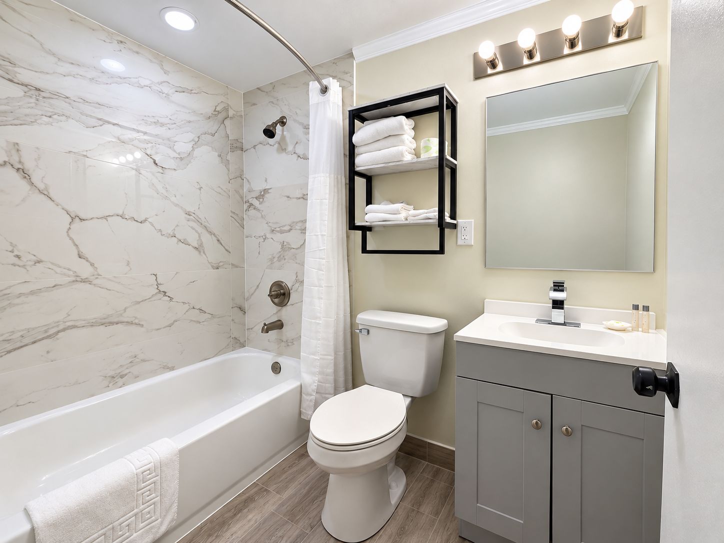 A bathroom with a bathtub, toilet, and vanity with a mirror.