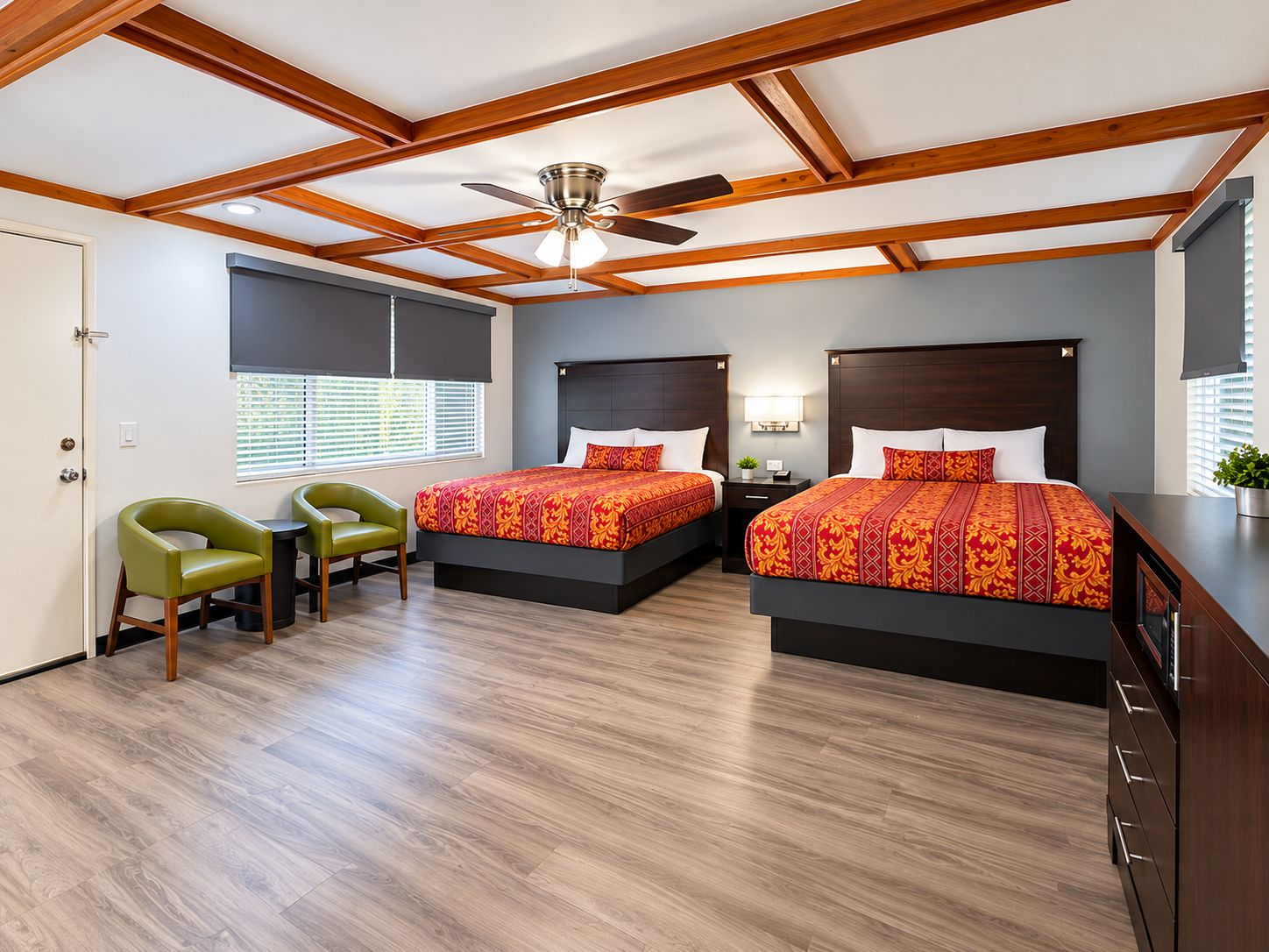 Ein Hotelzimmer mit zwei Betten, einem Deckenventilator, einem Schreibtisch und einem Stuhl.