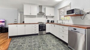 Eine moderne Küche mit weißen Schränken, Edelstahlgeräten, einer Holz Arbeitsplatte und einer eingebauten Mikrowelle.
