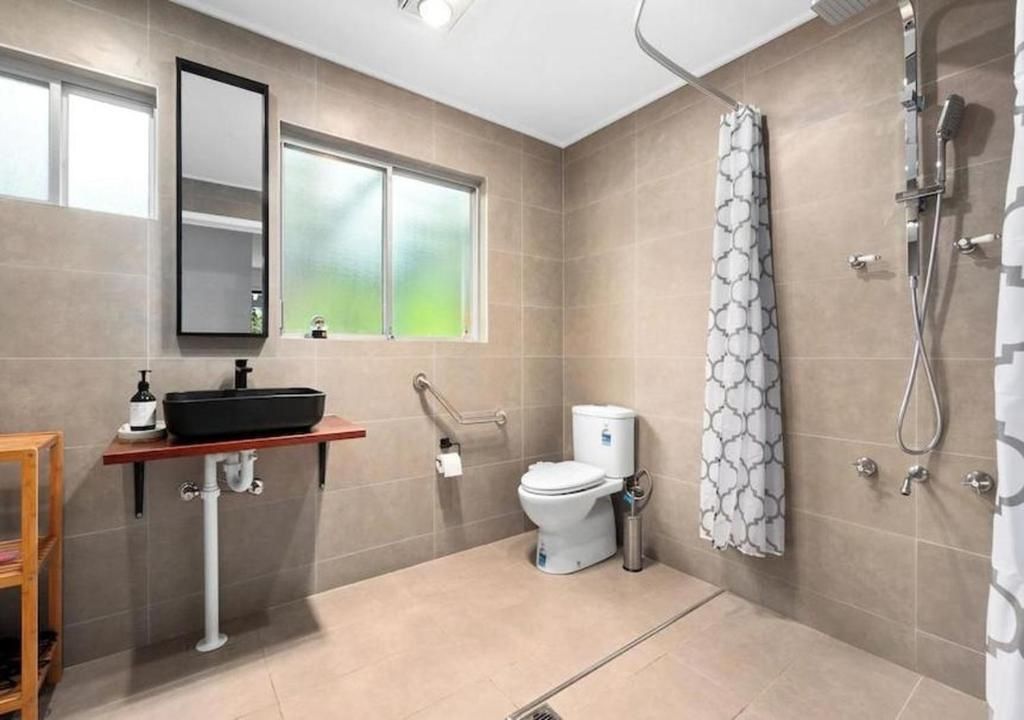 A modern bathroom with a toilet, sink, shower, and a window.