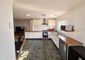 A compact kitchen with white cabinets, a stove, a microwave, and a dishwasher.
