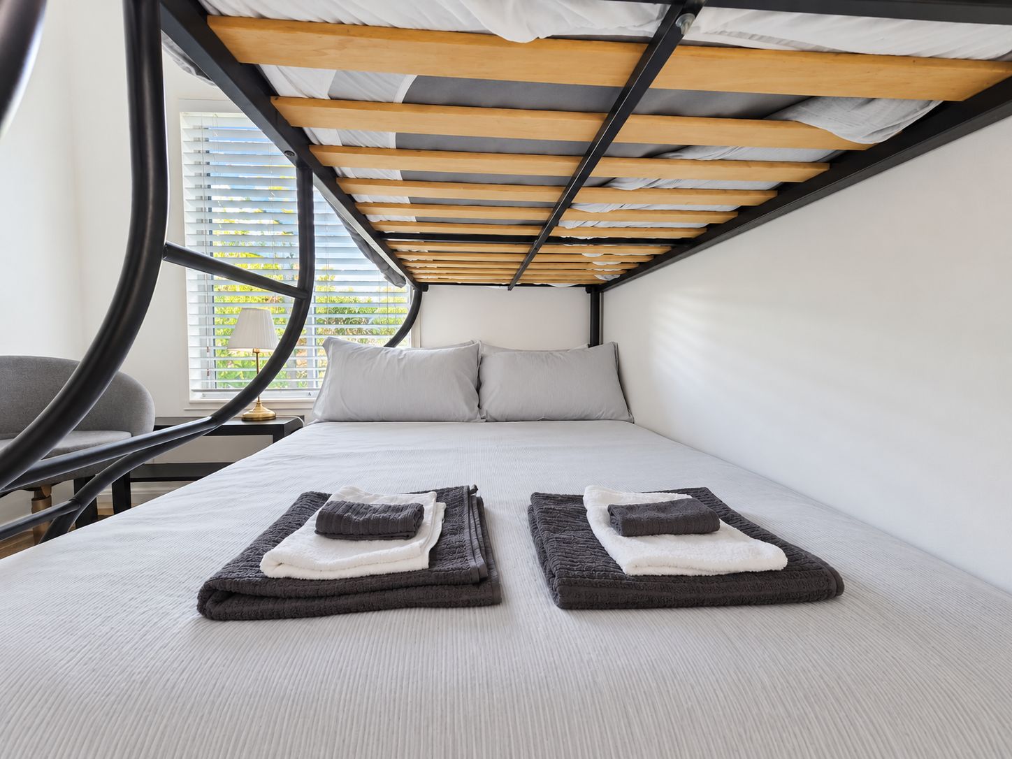 A compact bedroom with a bed, pillows, and a window with blinds.