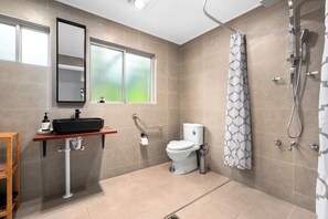 A modern bathroom with a toilet, sink, shower, and a window.