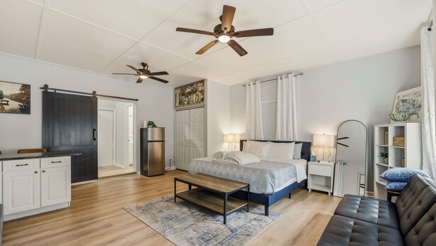 A modern, well-lit room with a bed, a sofa, a dining area, and a kitchen. - Luxurious Super Spacious Home (Tallahassee)