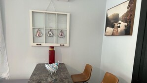 A dining area with a granite table, two brown chairs, a red water bottle, and a decorative window with floral vases. - Luxurious Super Spacious Home (Tallahassee)