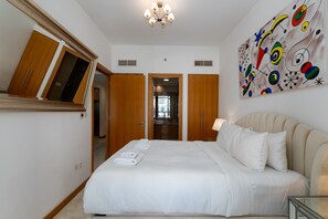 A hotel room with a large bed, a bedside table, a mirror, a ceiling light, and a colorful abstract painting on the wall. - 1BR Apt in Prime Location w/ Marina View Balcony (Dubai)
