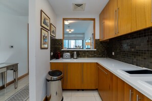 A compact kitchen with wooden cabinets, a white countertop, and a tiled backsplash.