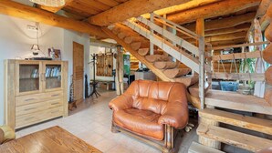 Een rustiek interieur met een leren bank, een houten trap en een houten kast.