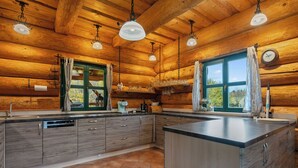 Een moderne keuken met houten wanden, een centraal kookeiland en hanglampen.