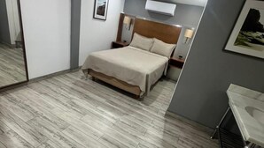 A modern bedroom with a bed, bedside tables, a mirror, and a small desk. - Hotel Colonial Inn  (Tijuana)