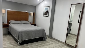 A bedroom with a bed, bedside tables, a mirror, and a picture on the wall. - Hotel Colonial Inn  (Tijuana)