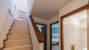 Una scala conduce a una camera da letto con un letto, un bagno con il water e un termosifone.