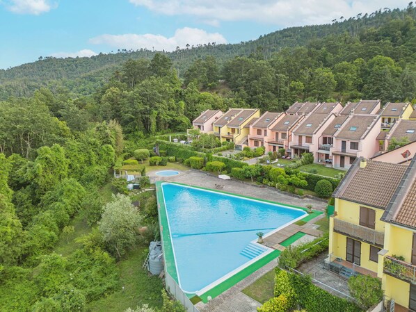A residential area with a swimming pool surrounded by lush greenery and terraced houses.