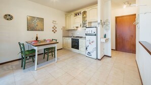 Una cucina compatta con mobili bianchi, un tavolo da pranzo con sedie e un frigorifero decorato con disegni.