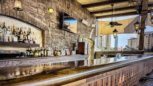 Un bar con pared de piedra, mostrador de madera y luces colgantes.