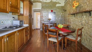 Une cuisine rustique avec des meubles en bois, un mur en pierre et un coin repas comprenant une table et des chaises.