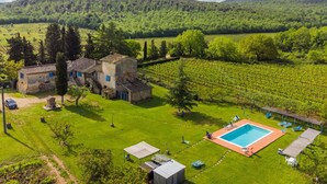 Une villa dotée d’une piscine, entourée de champs verdoyants et de vignobles, avec une chaîne de montagnes en toile de fond.
