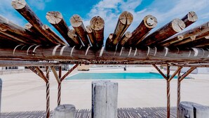 Een houten constructie met boomstammen, een zwembad en een heldere lucht.