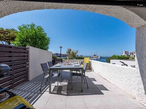 An outdoor patio with a table set for dining, a yellow chair, and a grill. - Palmyra by Interhome (Le Barcarès)