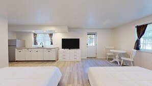 A hotel room with a kitchenette, a TV, a dining area, and two beds. - Comfortable Coastal Retreat with Two Queen Beds - Suite Room (Cape May)