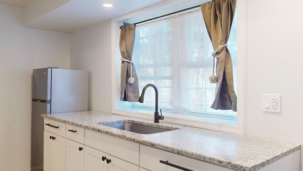 A kitchen with a granite countertop, stainless steel sink, and a built-in refrigerator. - Comfortable Coastal Retreat with Two Queen Beds - Suite Room (Cape May)