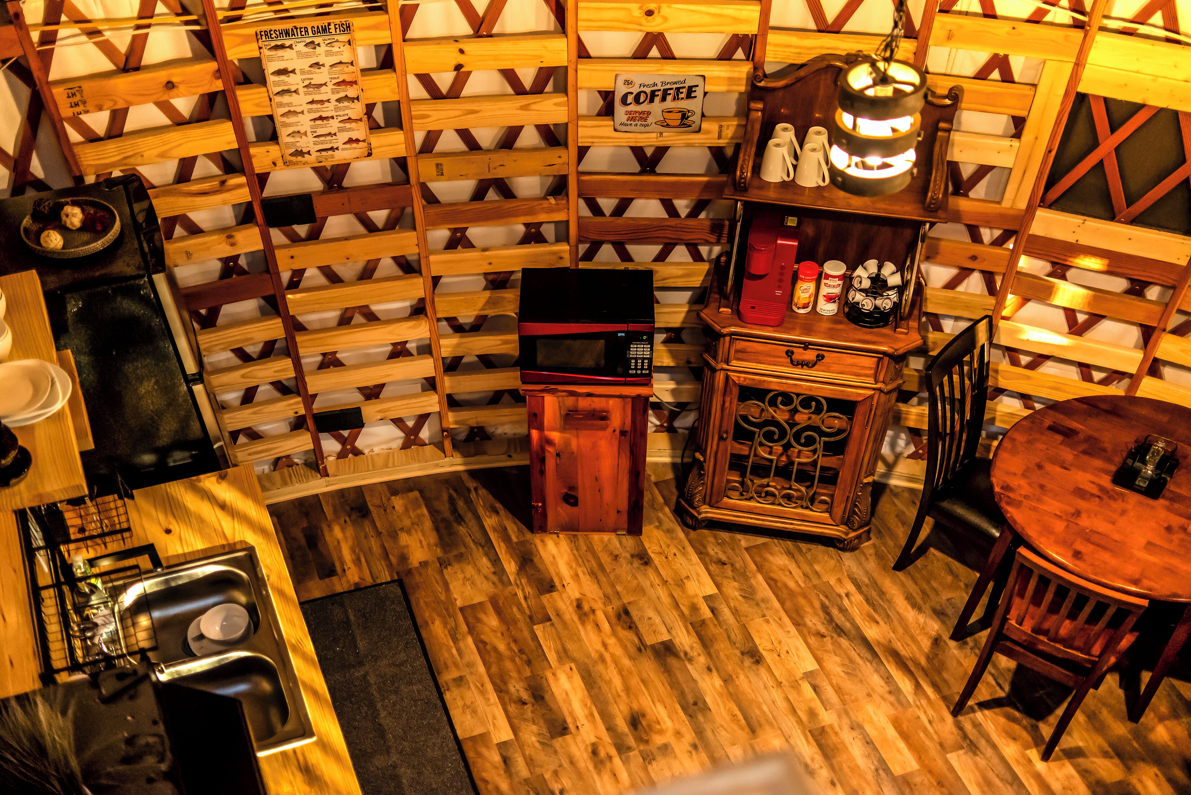 A cozy room with a wooden wall, a coffee station, a microwave, and a dining area with chairs and a table.