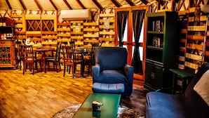 A cozy room with wooden floors, a green coffee table, a blue armchair, and a bookshelf.