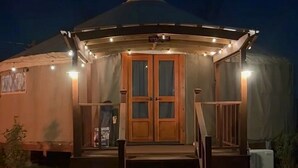 A yurt with a wooden door, a porch, and a staircase leading up to the entrance.