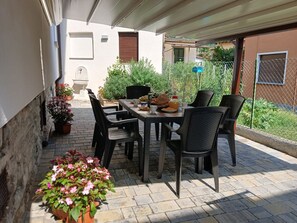 An outdoor patio with a table and chairs, surrounded by potted plants and a view of a residential area. - Apartment Irene by Interhome (Dongo)