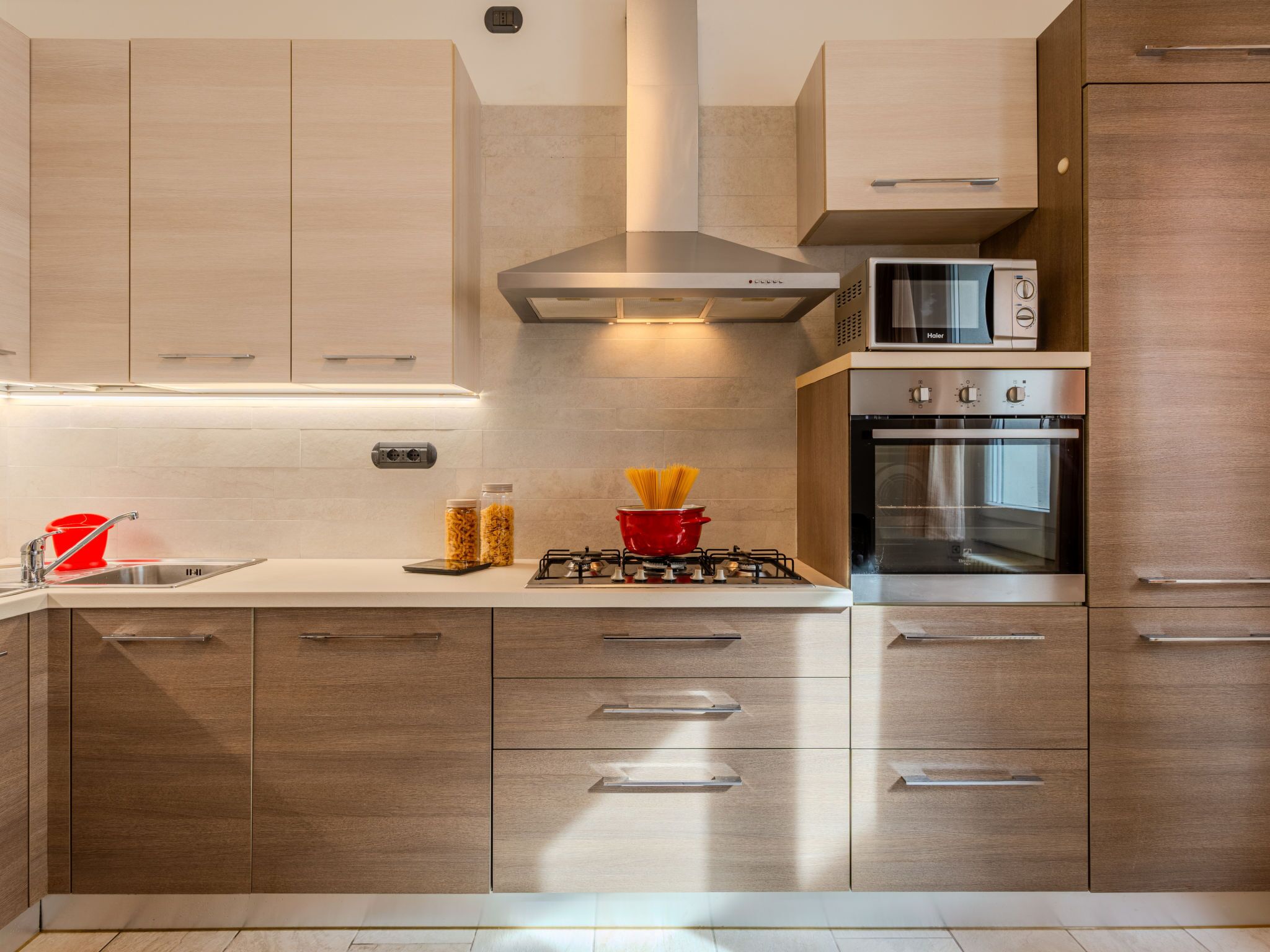 Una cocina moderna con armarios de madera, estufa a gas, microondas y horno.