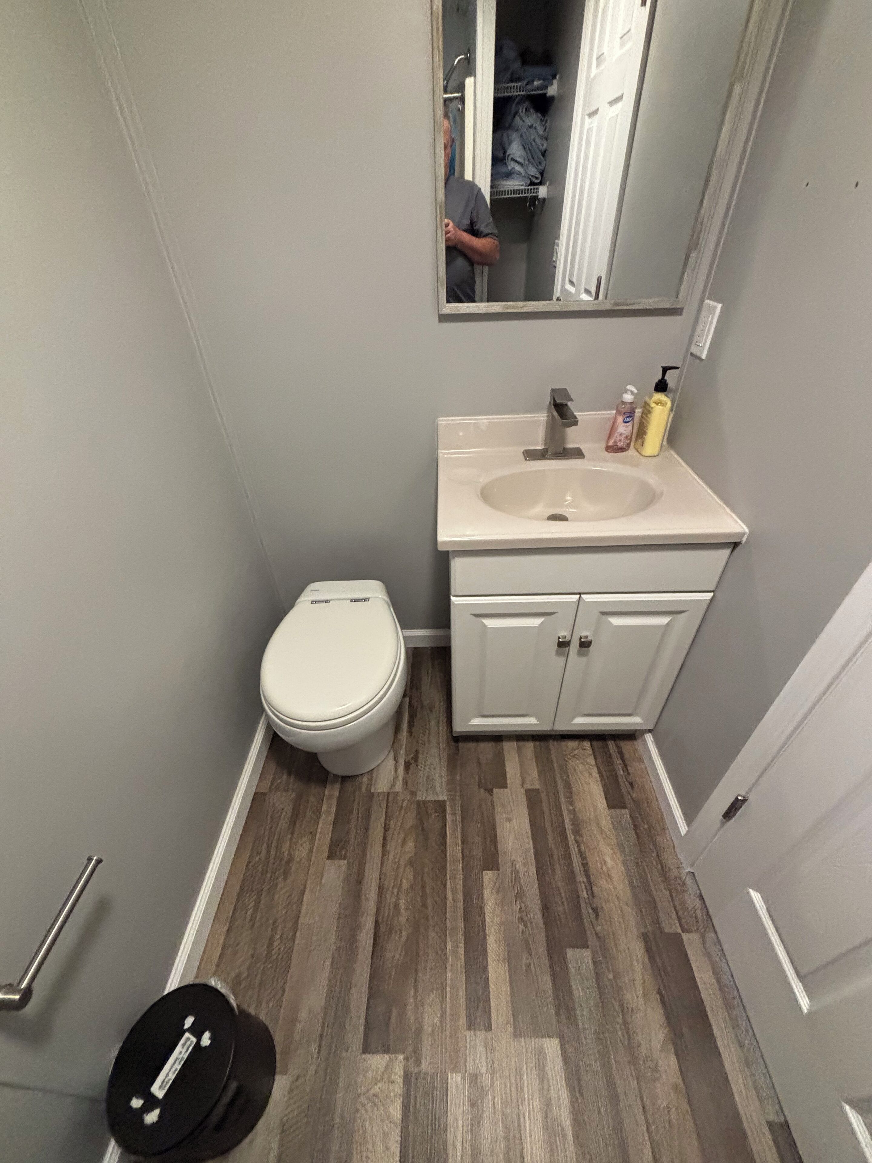 Een badkamer met een wit toilet, een wastafel met een spiegel erboven en een kastje eronder.