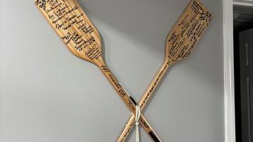 A wall-mounted wooden paddle with signatures, crossed over each other, and a tassel hanging from the center.