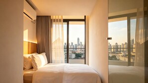 A hotel room with a bed, a city view, and a large window. - Amanda Hotel (Phnom Penh)