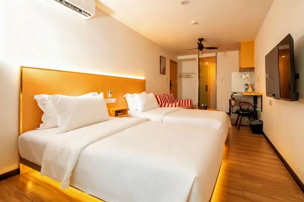 A hotel room with two beds, a desk, a chair, and a mirror.