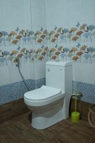 Un baño con inodoro, ducha y escoba.