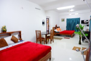 Habitación de hotel con dos camas, una mesa de comedor, sillas, un televisor y un ventilador de techo.