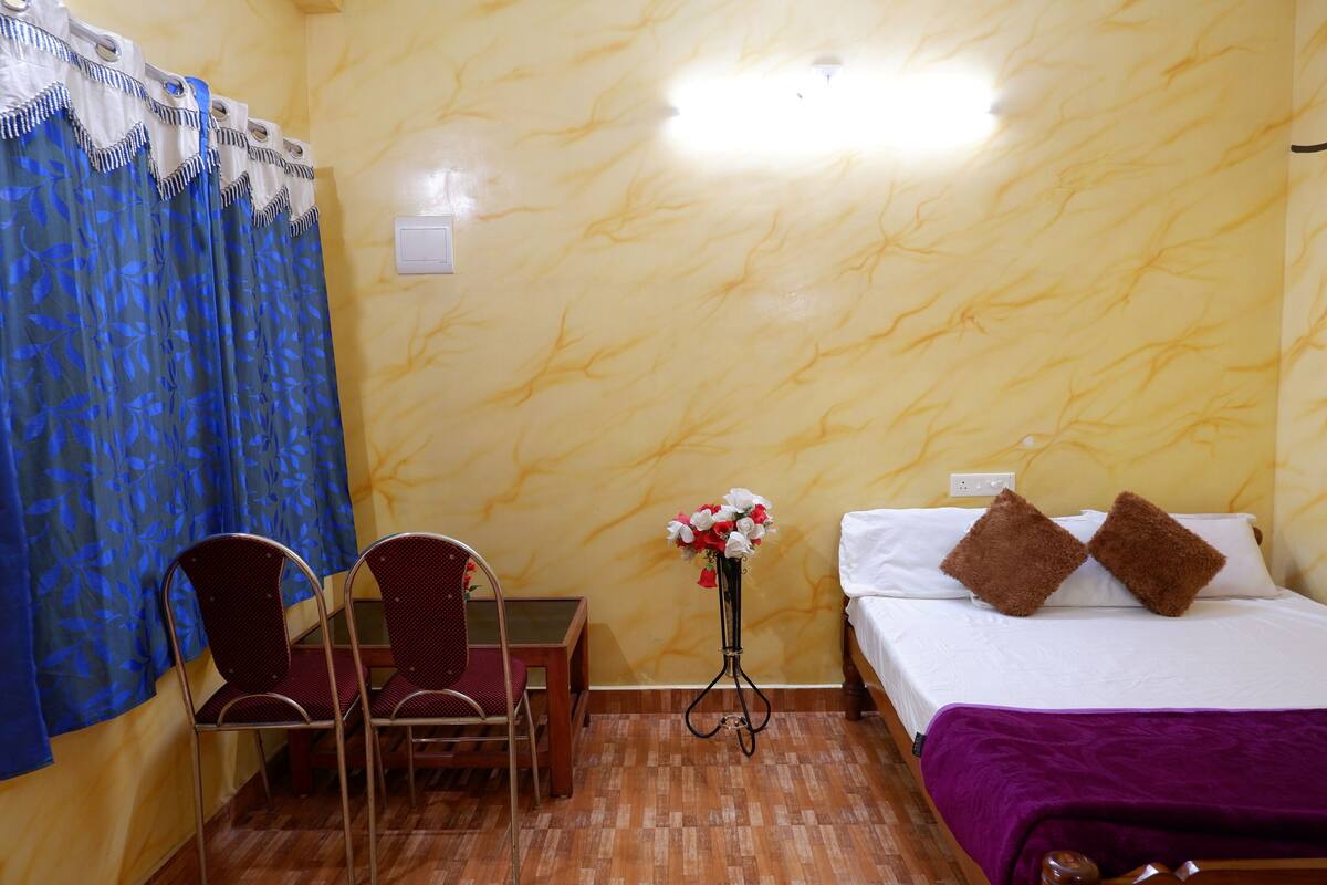 Ein Hotelzimmer mit Bett, Stuhl, Tisch und einem Blumenstrauß.