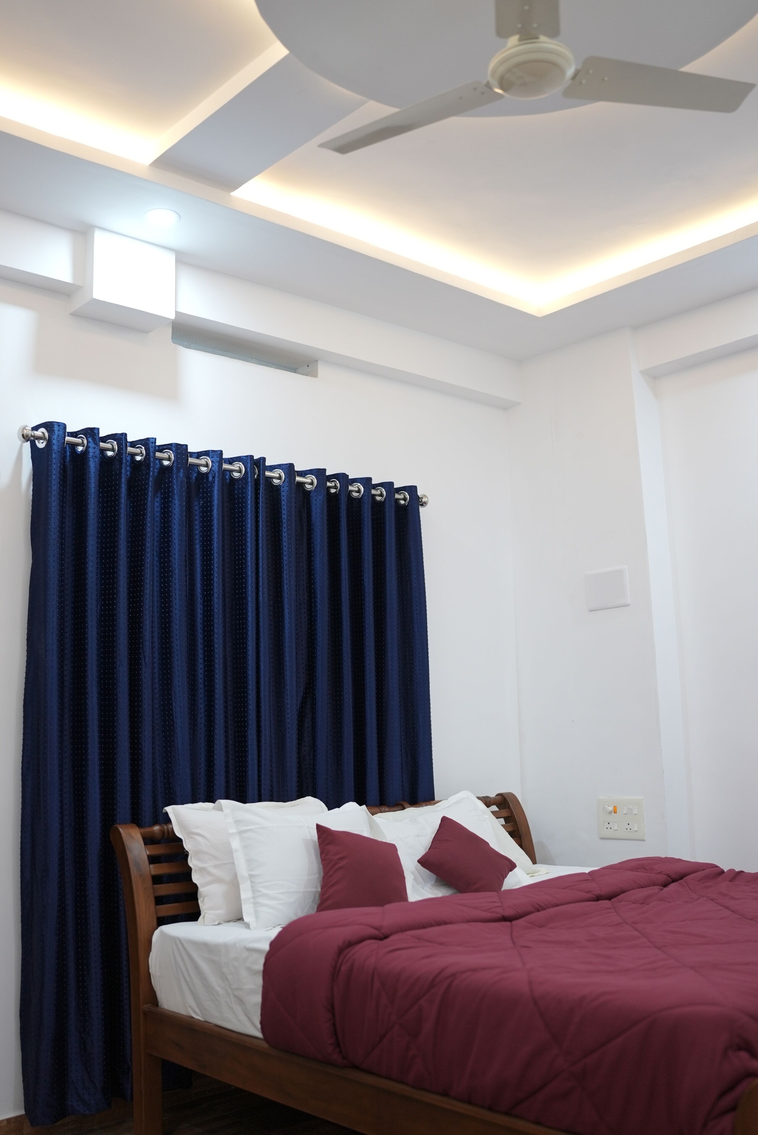 A bedroom with a bed, a ceiling fan, and a window with curtains.
