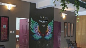 A reception area with a mural of colorful wings and the text "Find Wings Wind Valley." - WIND VALLEY FARMSTAY (Ramakkalmedu)