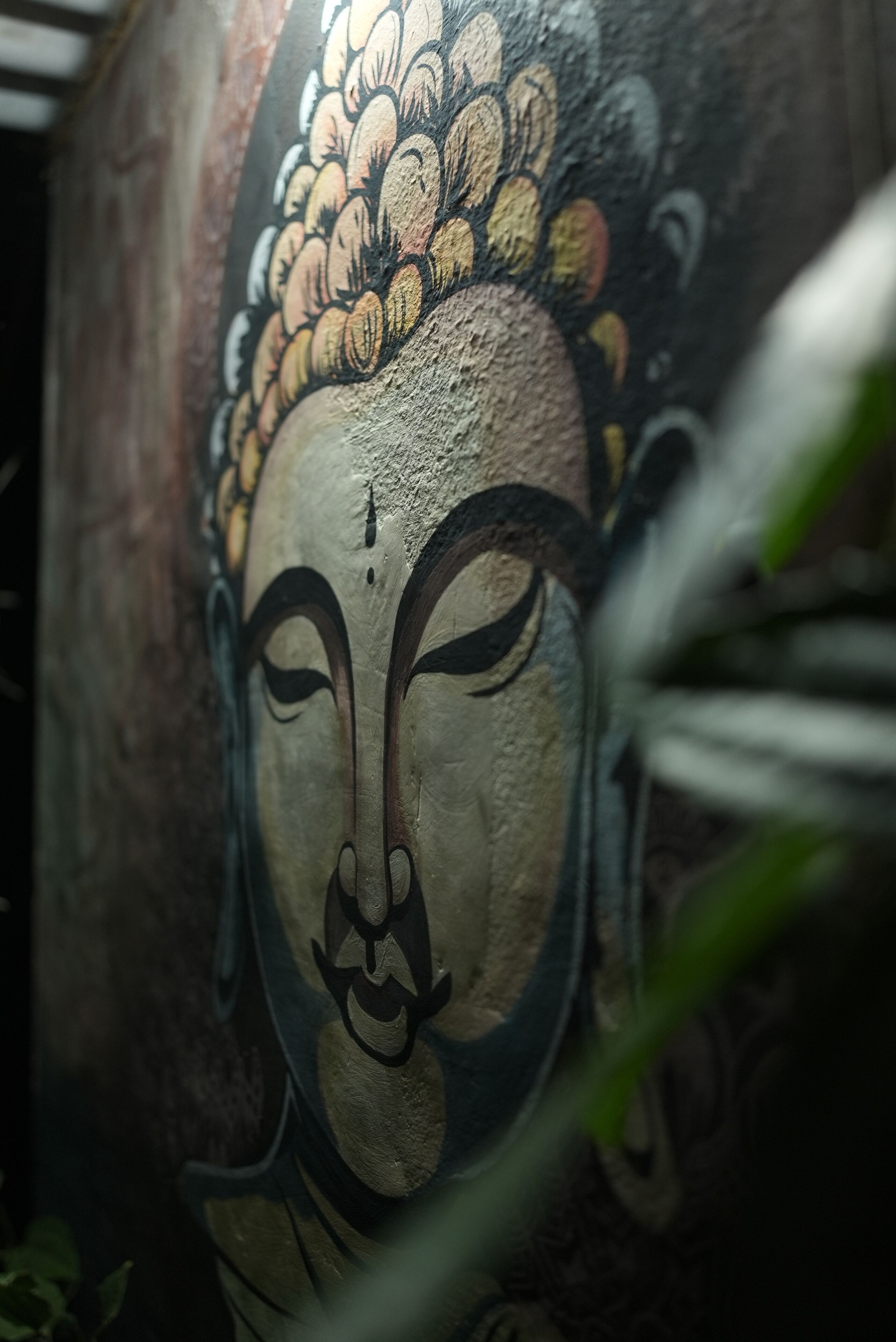 A close-up of a wall with a mural featuring a Buddha-like figure.